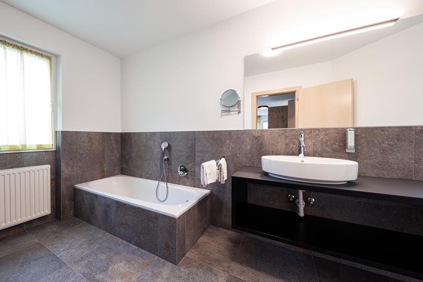 Badezimmer mit Waschbecken und Badewanne - Doppelzimmer SÜD PLUS Zirm